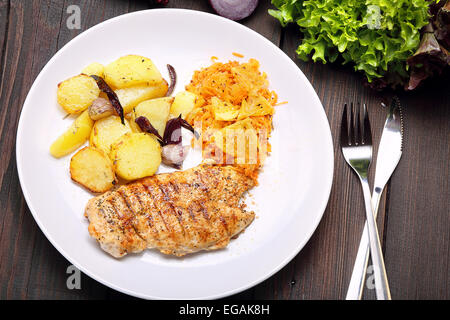 Portion gegrilltes Hähnchen, gebackene Kartoffeln und Karotten Salat Stockfoto