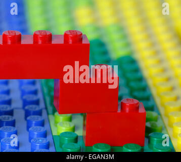 Teil einer Lego Konstruktion einer roten Brücke über einem blauen Fluss in eine grüne und gelbe Landschaftsmodell alle aus Legosteinen. Stockfoto