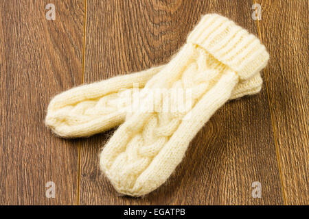 Stricken Handschuhe auf hölzernen Hintergrund weiß Stockfoto