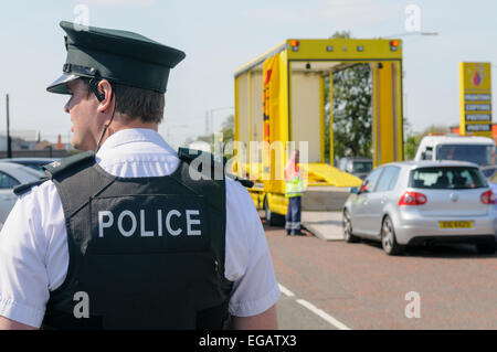 Polizist blickt auf, während sie eine beschlagnahmtes Fahrzeug nutzen, da es auf eine Erholung LKW geladen wird. Stockfoto