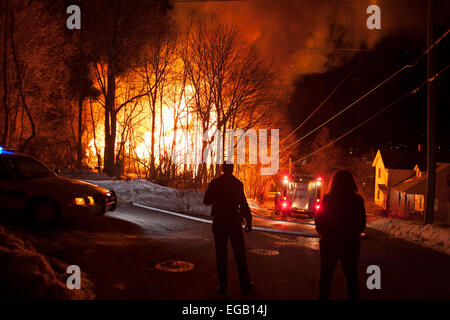 Ein tödliches Feuer lodert in einer kleinen Stadt in New England an einem Wintertag mit Nacht Polizei und Polizeiauto im Vordergrund. Stockfoto