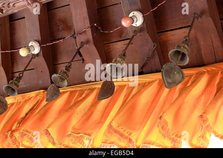 Metallische Wind Glocken von Holzdach Traufe zusammen mit farbigen Glühbirnen-Haus in der Altstadt. Dhulikhel-Kavrepal Stockfoto