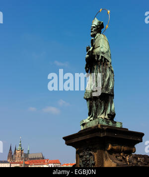 Statue des Johannes von Nepomuk auf der Karlsbrücke in Prag. St Vitus Cathedral ist im Hintergrund. Stockfoto