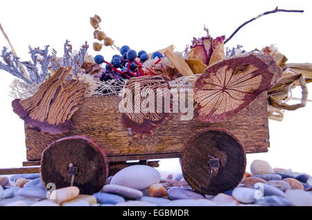 Miniatur-Einkaufswagen voller Blumen auf einem Felsenweg Stockfoto