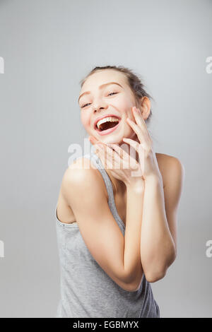 hübsche junge erregte Frau, vor grauem Hintergrund isoliert Stockfoto