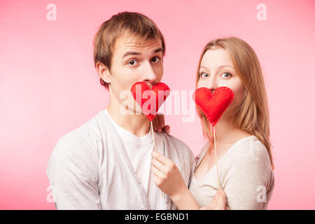 Paar versteckt ihre Lippen hinter kleinen roten Herzchen Stockfoto