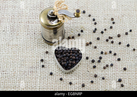 Ganze schwarzer Pfeffer und eine Pfeffermühle auf einem Vintage Tischdecke Stockfoto