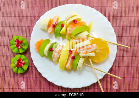 Drei Spieße voller verschiedener Früchte, platziert auf einem weißen Teller Stockfoto