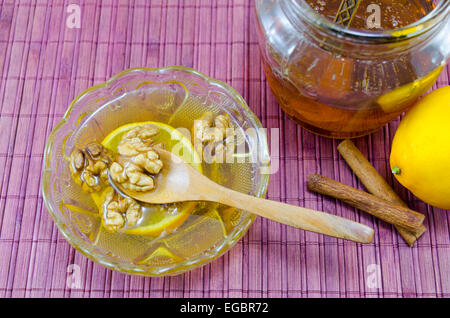 Walnüsse, Honig und Zimt in einem Glas auf einem Holztisch Stockfoto