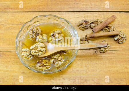 Walnüsse, Honig und Zimt in einem Glas auf einem Holztisch Stockfoto