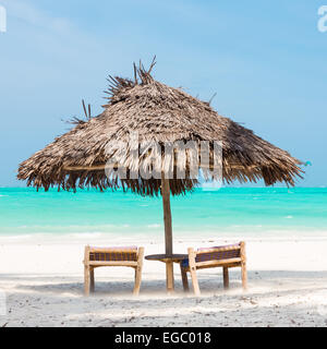 Zwei Liegestühle und Sonnenschirm am tropischen Strand. Stockfoto