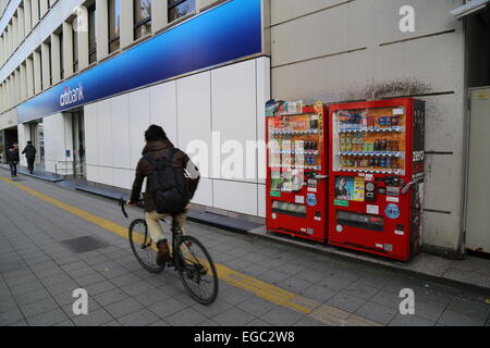 Ein Mann mit seinem Fahrrad vorbei an zwei Automaten in Tokio, Japan. Stockfoto