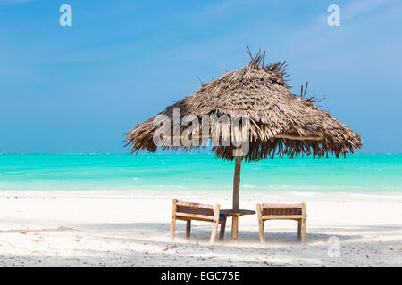 Zwei Liegestühle und Sonnenschirm am tropischen Strand. Stockfoto