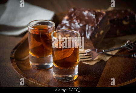 Glas Rum auf Holztablett mit Schokoladen-Brownies im Hintergrund, selektiven Fokus Stockfoto