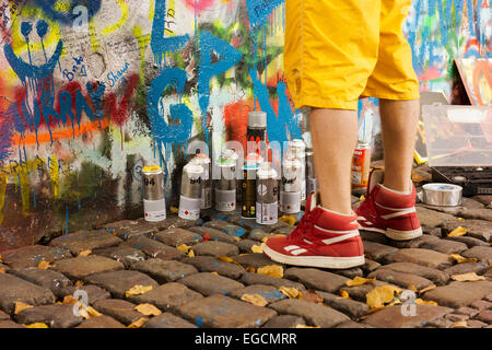 Füße und Lack Dosen eine Sprayfarbe Künstler arbeiten bei der Lennon-Mauer in Prag. Stockfoto