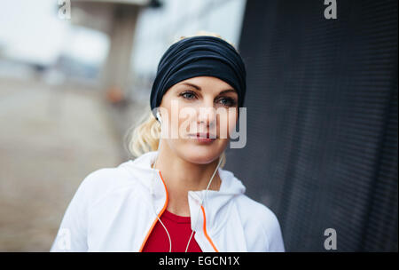 Close-up Portrait attraktive und sportliche Frau trägt Stirnband und Musik über Kopfhörer hören. Fitness-weiblich. Stockfoto