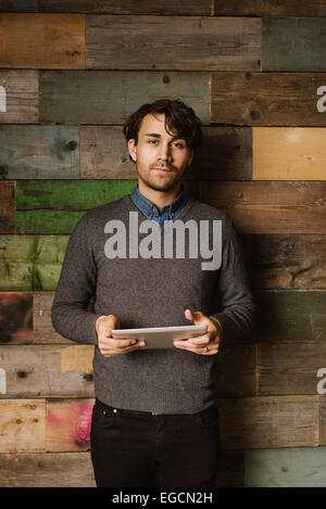 Porträt von zuversichtlich junger Mann hält eine digitale-Tablette Blick in die Kamera. Führungskraft mit Tablet-Computer.