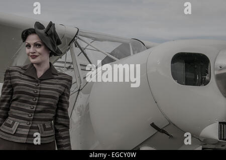 Ein Mädchen in Kostümen neben einem Flugzeug am Goodwood Revival 2014 posieren. Frauen in klassischen Vintage Zeitraum Kleid in der Luftfahrt Park Stockfoto