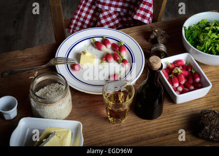 Platte mit Radieschen, Butter und Apfelwein auf einem rustikalen Tisch Stockfoto