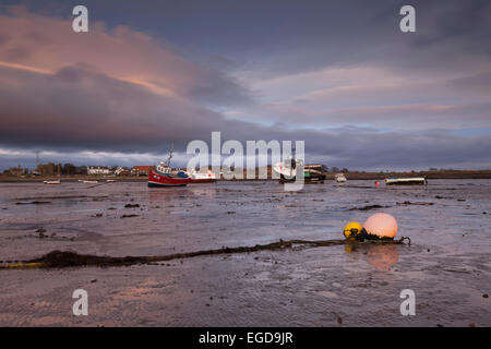 Sonnenaufgang über dem Hafen von Lindisfarne mit Booten liegen auf dem flachen Schlamm bei Ebbe, Lindisfarne, Holy Island, Northumberland, England, Vereinigtes Königreich Stockfoto