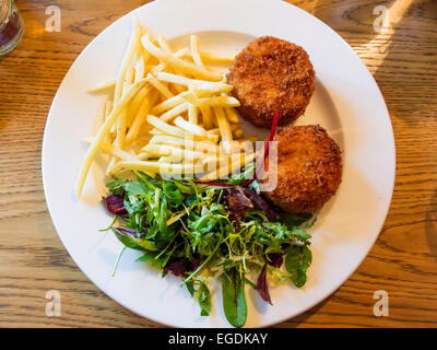 Eine einfache Kneipe Mittagessen der hausgemachte Fischfrikadellen mit Salat garnieren und französische gebratene Kartoffeln Stockfoto