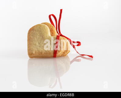 Festliche Kekse in Form von Herzen, mit einem roten Band mit einer Schleife gebunden. Stockfoto