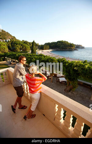 Paar auf der Suche auf den Blick vom Balkon der Villa Milocer, Aman Sveti Stefan, Sveti Stefan, Budva, Montenegro Stockfoto