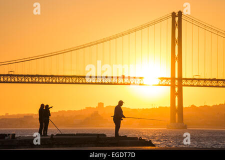 Silhouette der Fischer am Ufer Cacilhas mit Ponte 25 de Abril Brücke über den Tejo bei Sonnenuntergang, Cacilhas, Almada (bei Lissabon), Portugal Stockfoto