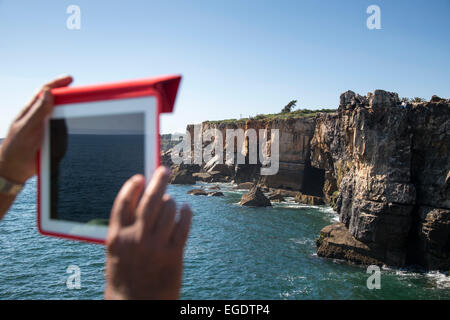 Mann ein Foto von der Boca do Inferno (Hells Mouth) Abgrund und Klippen mit iPad, Cascais, in der Nähe von Lissabon, Lisboa, Portugal Stockfoto