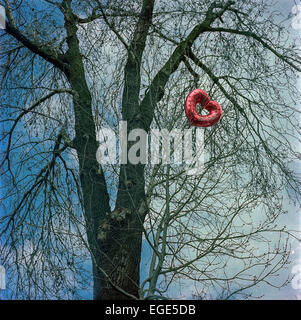 Aufblasbare rotes Herz Ballon in kahlen Baumkrone. Stockfoto