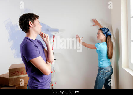 Junges Paar diskutieren wo man Objekte auf Wand platzieren Stockfoto