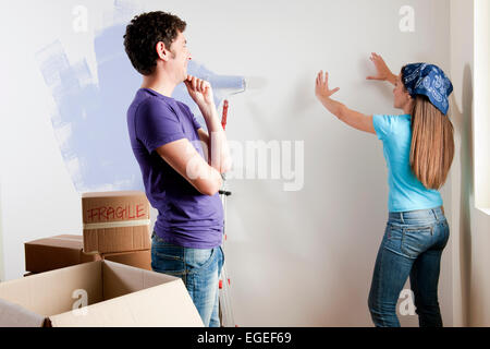 Junges Paar diskutieren wo man Objekte auf Wand platzieren Stockfoto