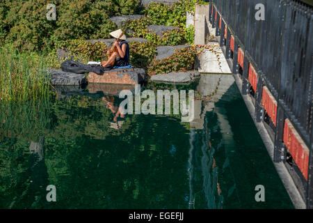 Mann mit Bambushut Gitarre auf einem Felsen bei Lafontaine Park in Montreal, während der Indian Summer Stockfoto