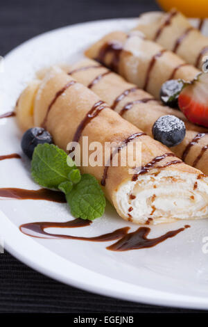 Leckere süße Pfannkuchen auf einen Teller mit frischen Früchten gerollt Stockfoto