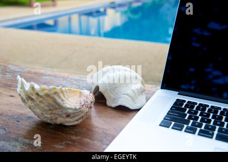 Laptop am Pool, im Urlaub mit Mobilitätskonzept arbeiten Stockfoto