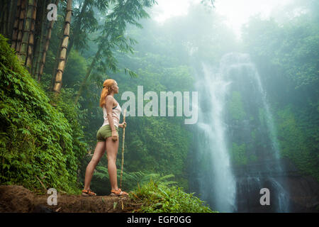 Weibliche Abenteurer am Wasserfall im Dschungel Bali suchen Stockfoto