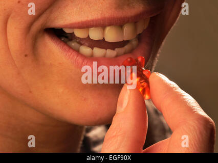 Symbolisches Bild über Zucker in Lebensmitteln: Frau Gummibärchen Essen. Stockfoto