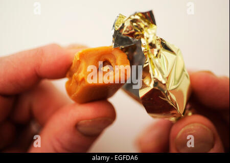 Männlich, Auspacken ein süßes Toffee Stockfoto