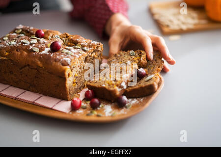 Junge Hausfrau Einnahme Stück frisch gebackenen Kürbis Brot Stockfoto