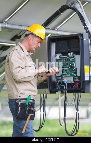 Techniker arbeiten unter Sonnenkollektoren Stockfoto