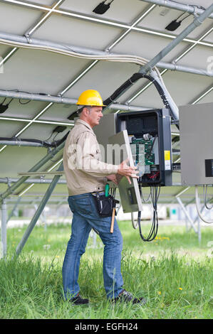 Techniker arbeiten unter Sonnenkollektoren Stockfoto