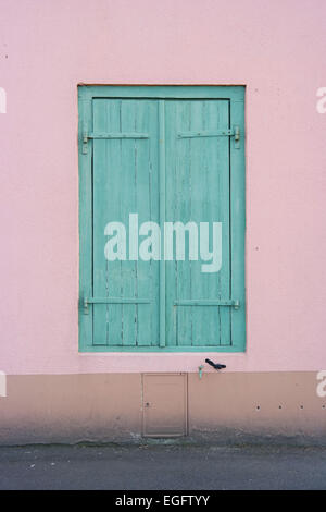 Fenster mit grünen Fensterläden geschlossen, inmitten einer rosa verputzten Wand in Saint-Malo, Frankreich Stockfoto