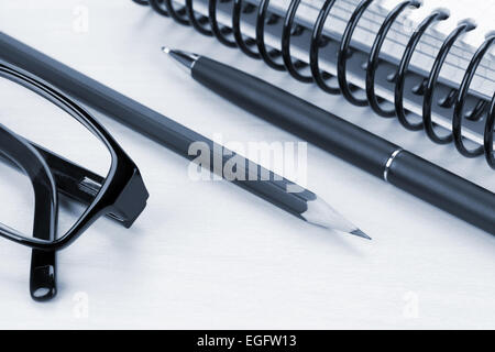 Bürotisch mit Brille, Notizblock und Zubehör. Blau getönten Bild Stockfoto