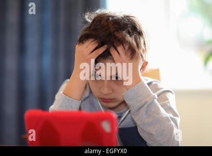 Kleiner Junge spielt mit Tablet-PC zu konzentrieren Stockfoto