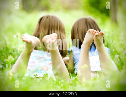 Zwei kleine Mädchen auf dem grünen Rasen im freien liegend Stockfoto
