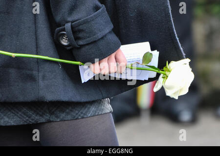 eine Person trägt eine weiße rose in Schwarz bei einer Beerdigung verkleidet Stockfoto