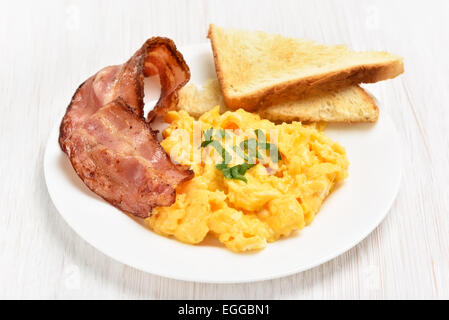 Rührei mit Speck und Toast auf weißen Teller, Nahaufnahme Stockfoto