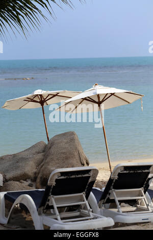 Sonnenliegen und Sonnenschirme zum Sonnenbaden am Strand in der Nähe von Meer Stockfoto
