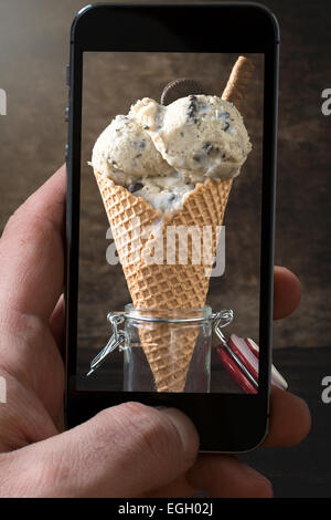 Eis mit Cookies in Glas auf hölzernen Hintergrund fotografieren mit Kamera Od Handy Stockfoto