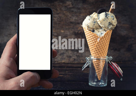 Eis mit Cookies auf hölzernen Hintergrund mit Leerzeichen auf dem Handy-Bildschirm Stockfoto